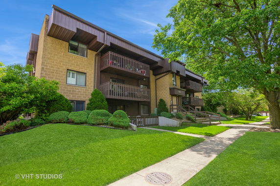 Front view of a multi-story residential building with balconies and a sloped roof.