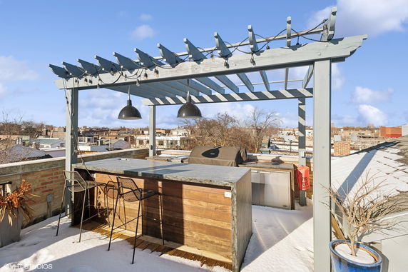 Rooftop area with a pergola, bar counter, stools, and outdoor grill.