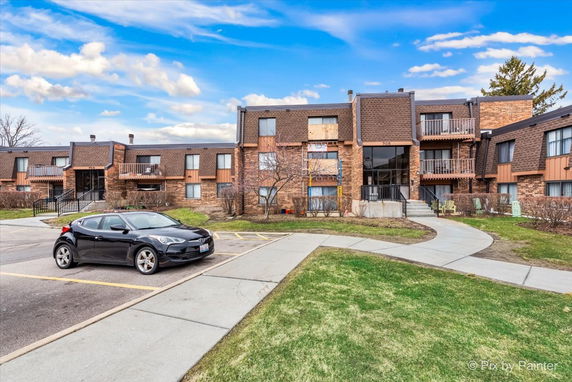 Front view of a two-story residential building with balconies and a parking area.