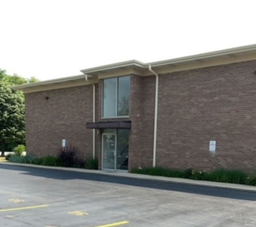 Front view of a two-story brick building with large windows.