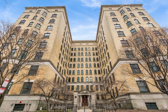 Front view of a multi-story residential building with an entrance and symmetrical design.