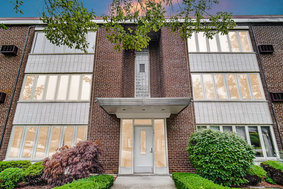 Front view of a brick building with large windows and an entrance canopy.
