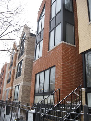 Front view of a multi-story brick building with large windows.
