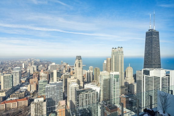 Panoramic view of a cityscape with tall buildings and a body of water in the background.