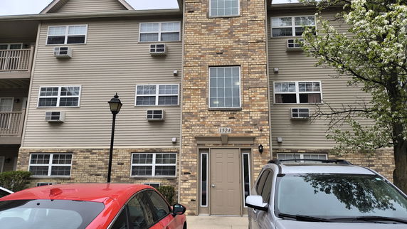 Front view of a multi-story residential building with brick and siding exterior.