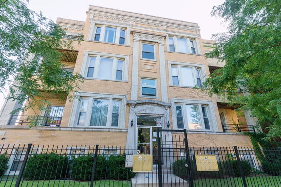 Front view of a multi-story apartment building with a gated entrance.