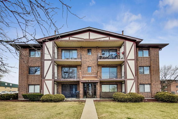 Front view of a multi-story brick apartment building with balconies.