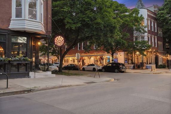 Street view of buildings with a mix of restaurants and shops, featuring a 'Love Street' sign and trees.