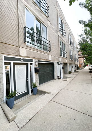 Front view of a multi-story building with balconies and garage doors.
