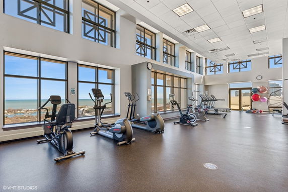 Exercise room with large windows, gym equipment, and view of the outdoors.