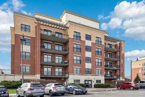 Front view of a multi-story brick apartment building with balconies.