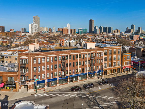 Front view of a multi-story brick building with retail spaces on the ground floor.