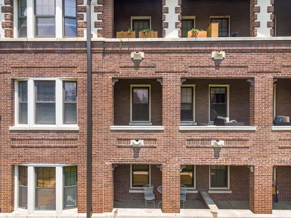 Front view of a multi-story brick building with multiple windows and small balconies.