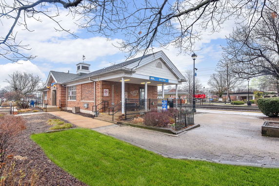 Front view of a small brick building with a porch and steps leading up to it.