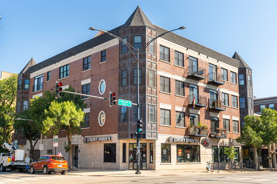Front view of a multi-story commercial building with a brick facade and retail spaces on the ground floor.