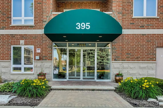 Front view of a building entrance with glass doors and a green awning.