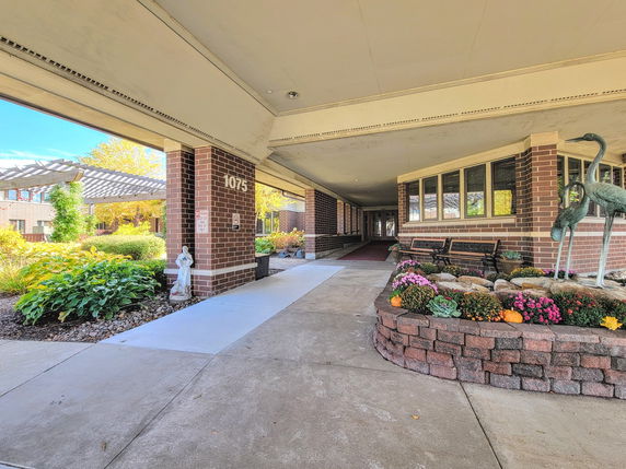 Entrance view of a brick building with large windows and decorative garden elements.