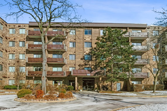 Front view of a multi-story brick apartment building with balconies.