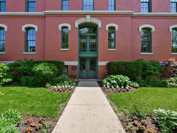 Front view of a red brick school building with large windows and a central entrance.
