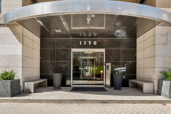 Front view of a building entrance with a modern glass door and metal canopy.