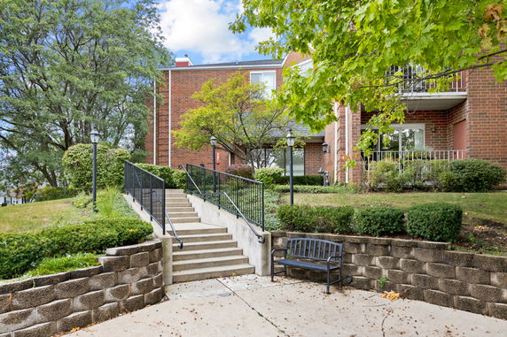 Front view of a brick residential building with stairs leading to the entrance.