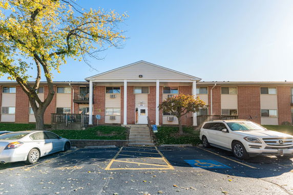 Front view of a two-story apartment building with brick facade and parking area.