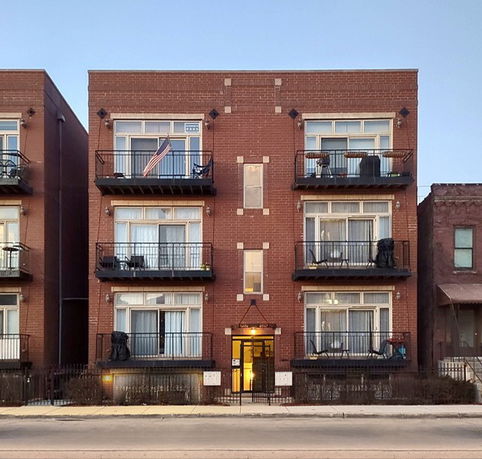 Front view of a multi-story brick apartment building with balconies.
