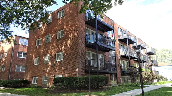 Front view of a brick apartment building with balconies.
