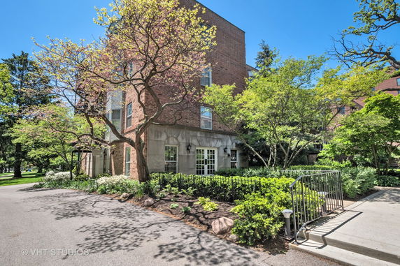 Front view of a multi-story brick building with large windows and landscaped surroundings.