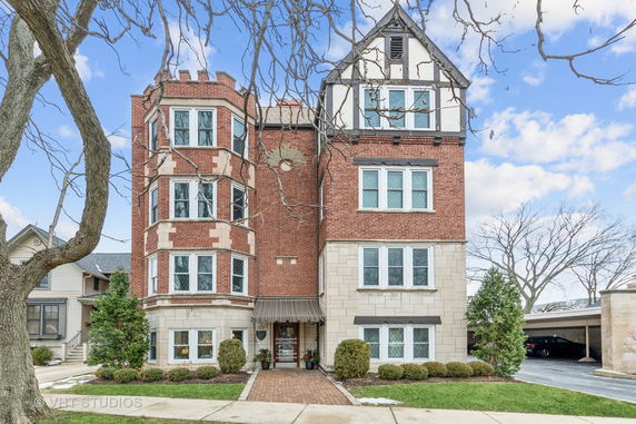 Front view of a multi-story brick building with bay windows and a central entrance.