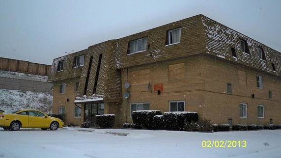 Front view of a snow-covered multi-story building with parked car.