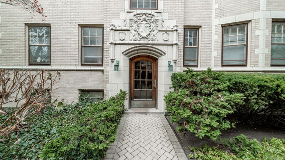 Front view of a building entrance with decorative stonework and a wooden door.