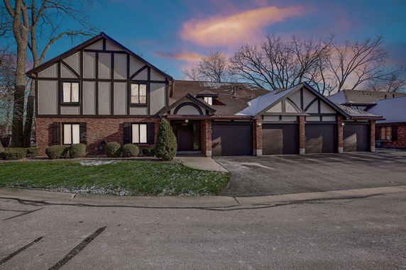 Front view of a two-story house with a three-car garage and Tudor-style architecture.