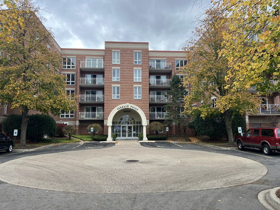 Front view of a multi-story brick building with balconies and an arched entrance.