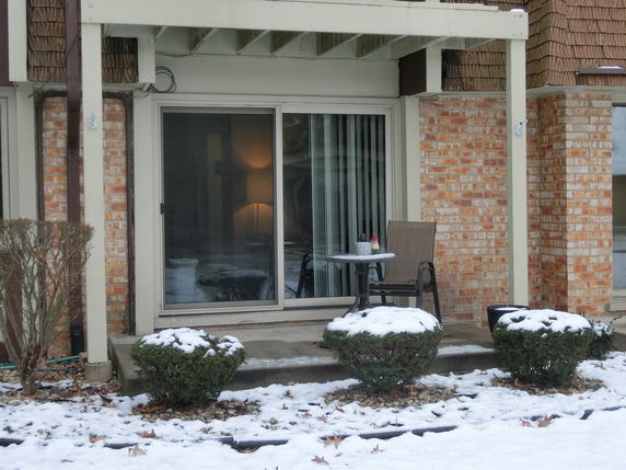 Front view of a building with brick exterior and sliding glass doors leading to a small patio area.