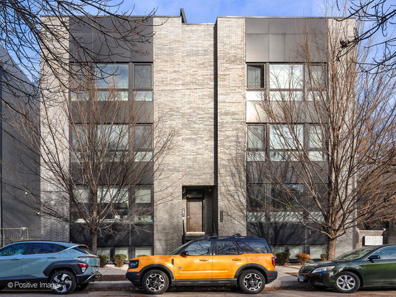 Front view of a modern, multi-story building with large windows and brick facade.