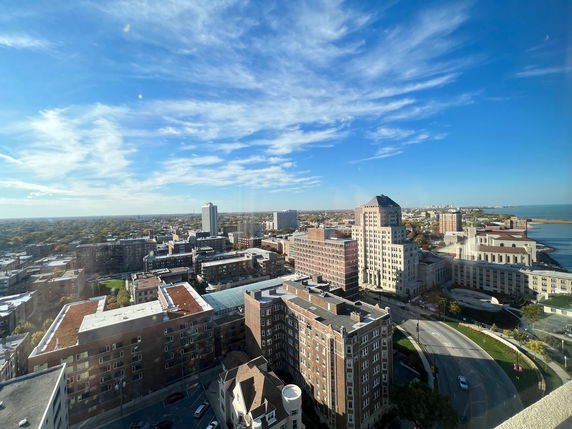 Panoramic view of a cityscape with multiple buildings and a body of water in the distance.