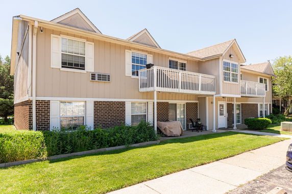 Front view of a two-story building with balconies and a mix of brick and siding exterior.