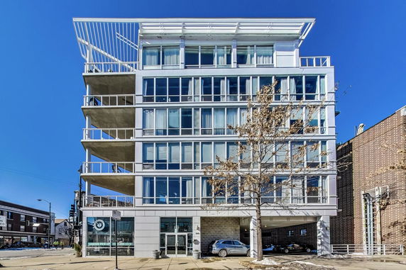 Front view of a modern multi-story building with large glass windows and balconies.