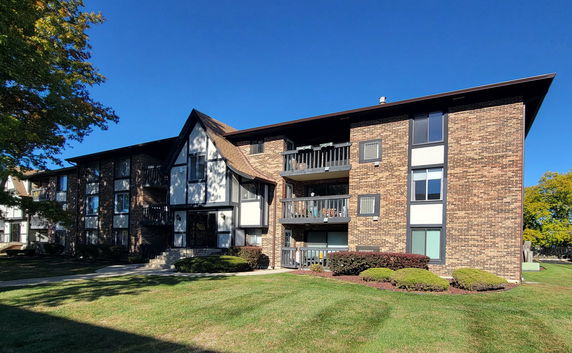 Front view of a multi-story apartment building with balconies and brick facade.
