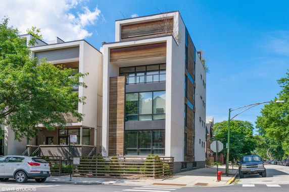 Front view of a modern multi-story building with large windows and wood paneling.