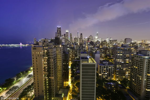 Panoramic view of city skyline with high-rise buildings and waterfront at night.