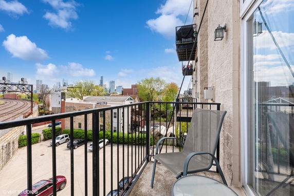 View from a balcony overlooking a city skyline and adjacent railway tracks.