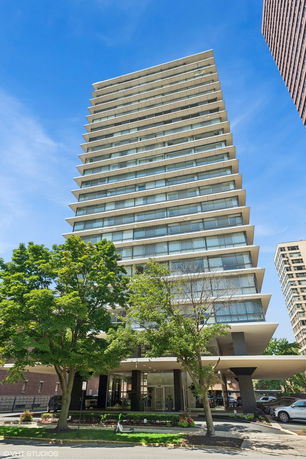 Front view of a high-rise building with multiple balconies and a glass facade.