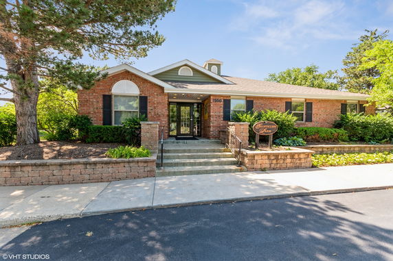 Front view of a brick house with a central entrance and steps leading up.