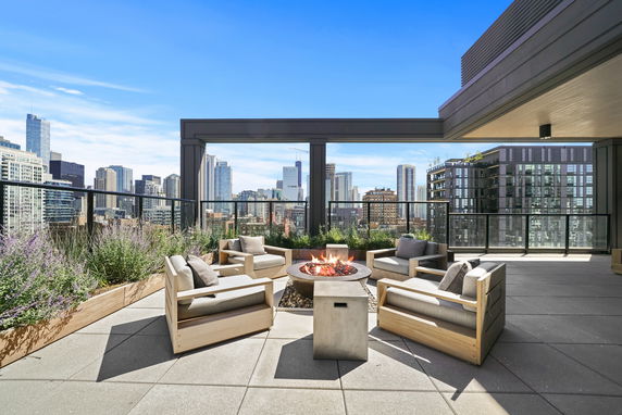 Rooftop with seating area and fire pit overlooking city skyline