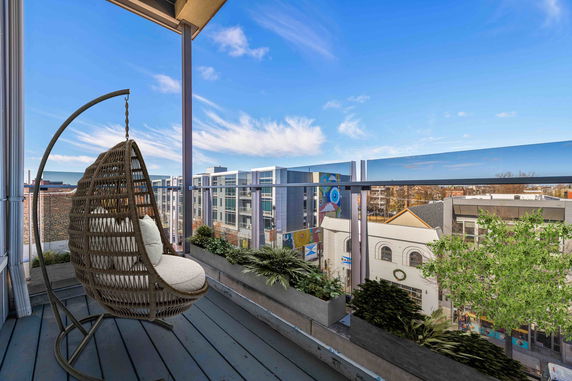 Wide balcony view overlooking surrounding buildings with a hanging chair on the balcony.