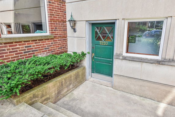 Front view of a building entrance with a green door and brick facade.