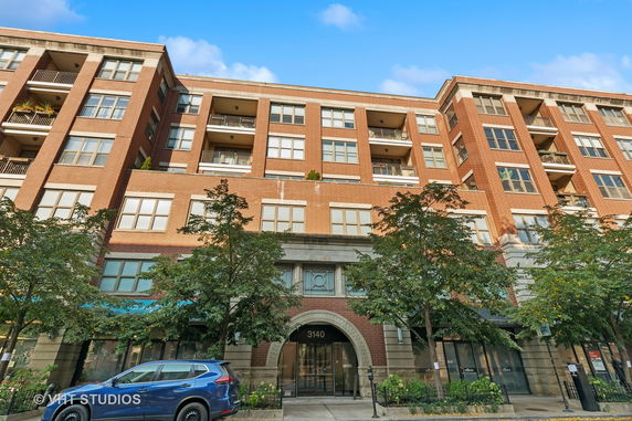 Front view of a multi-story brick building with balconies and large windows.
