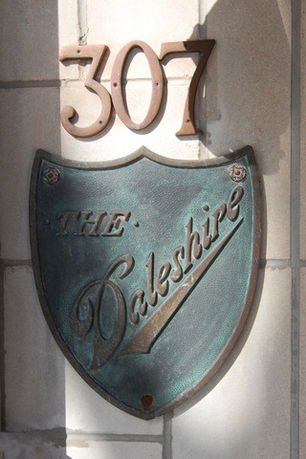 Close-up view of a shield-shaped plaque on the exterior wall of a building, displaying the number 307 and the name 'The Dalshire.'